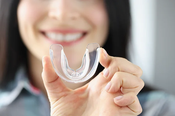 Close up of a simple mouth guard being held up by an smiling female patient at Timothy H. Kindt, DDS in Mesa, AZ