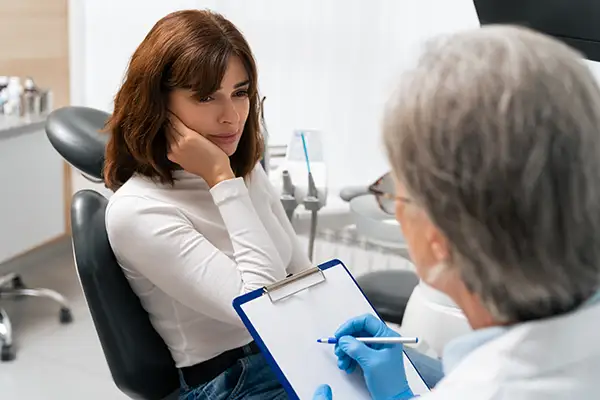 Female patient consulting with a dentist about restoring missing teeth during a dental appointment in a clinic.
